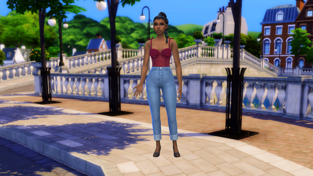 Un sim en jeans bleu taille haute et en corset rouge avec les cheveux tressés. Ce sim se tient près de l'eau dans le monde des Sims 4 de Britechester