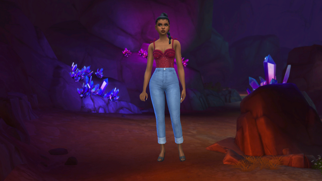 Un sim avec un jean taille haute bleu et un body corset rouge avec les cheveux tressés. Derrière ce sim se trouve l'image du monde Forgotten Grotto des Sims 4 en tant que fond d'écran CAS.