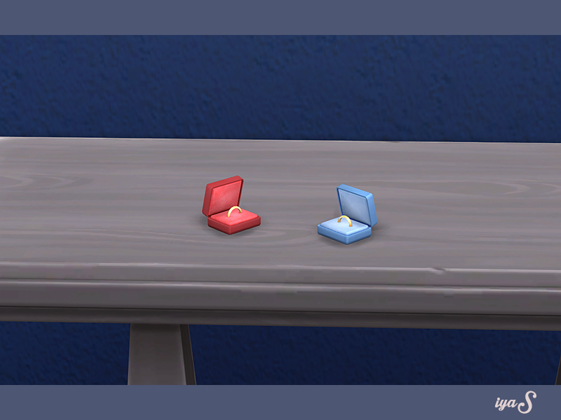 Une table en bois clair avec deux petites boîtes à bagues dessus, une rouge et une bleue.