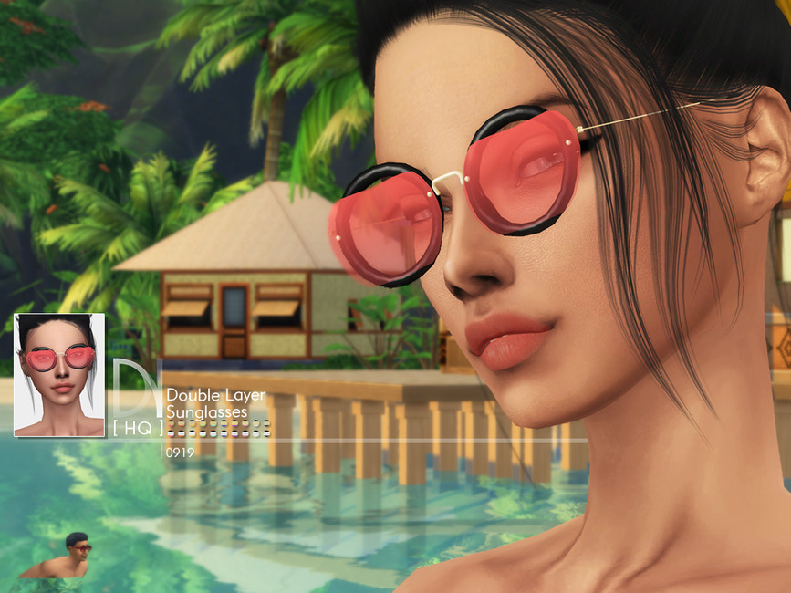 Un Sim debout sur une plage avec un paysage tropical en arrière-plan. Il porte une paire de lunettes rondes noires avec une monture rouge sur le dessus.